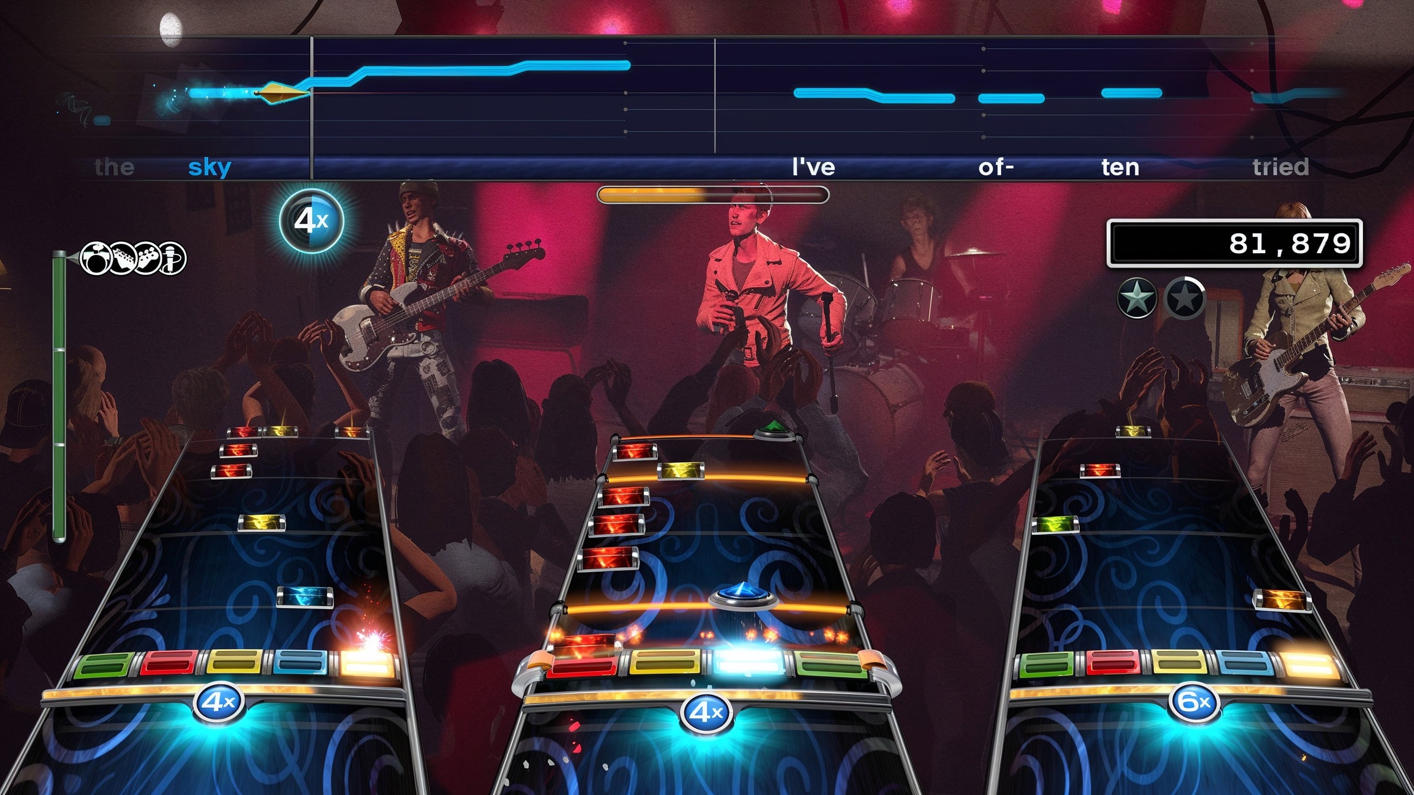Rock Band 4 gameplay scene with three note highways, a live band, crowd, and score UI